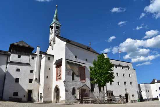Historische weiße Festung mit Uhrturm und Wandfresken unter blauem Himmel